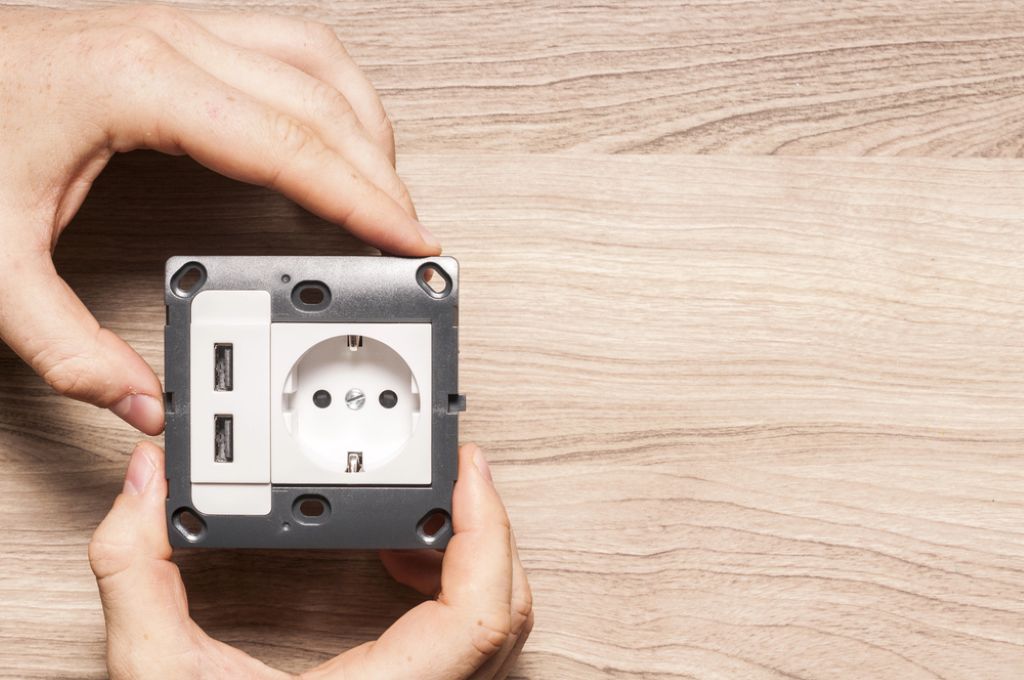 Image of a wall socket with two USB charger ports, featuring Anderson Lighting & Electric and highlighting the electrical services offered on their website.